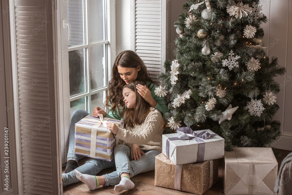 Mother and daughter unwrapping gift Mother and daughter unwrapping gift