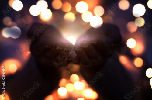 Magic particles emanating from female hands. Christmas background with bokeh