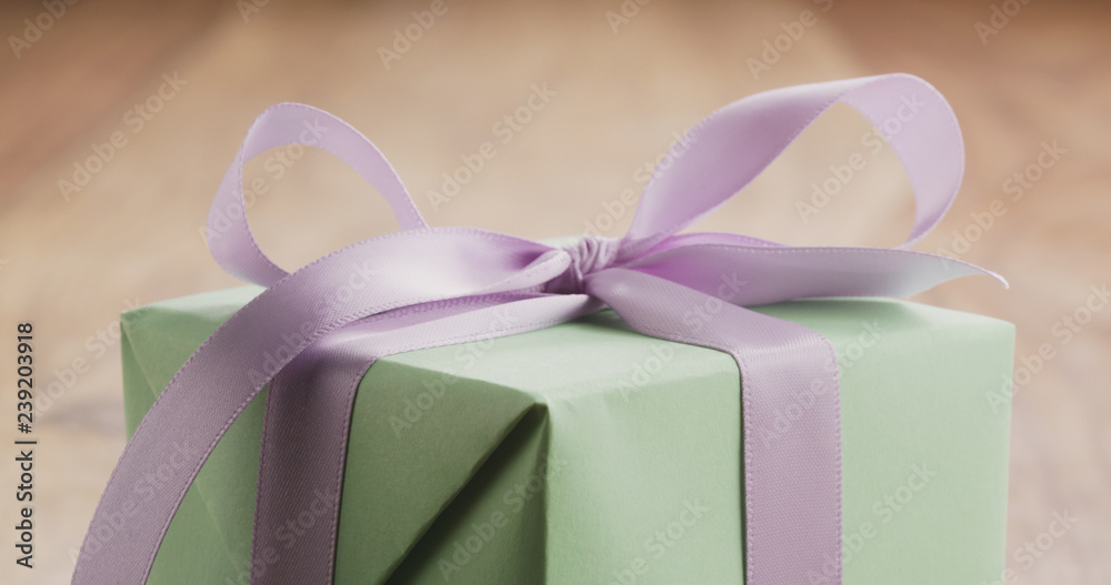 Closeup of green gift box with purple ribbon bow on old wood table Closeup of green gift box with purple ribbon bow on old wood table