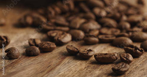 Closeup   of overturned cappuccino cup with roasted coffee beans on wood table