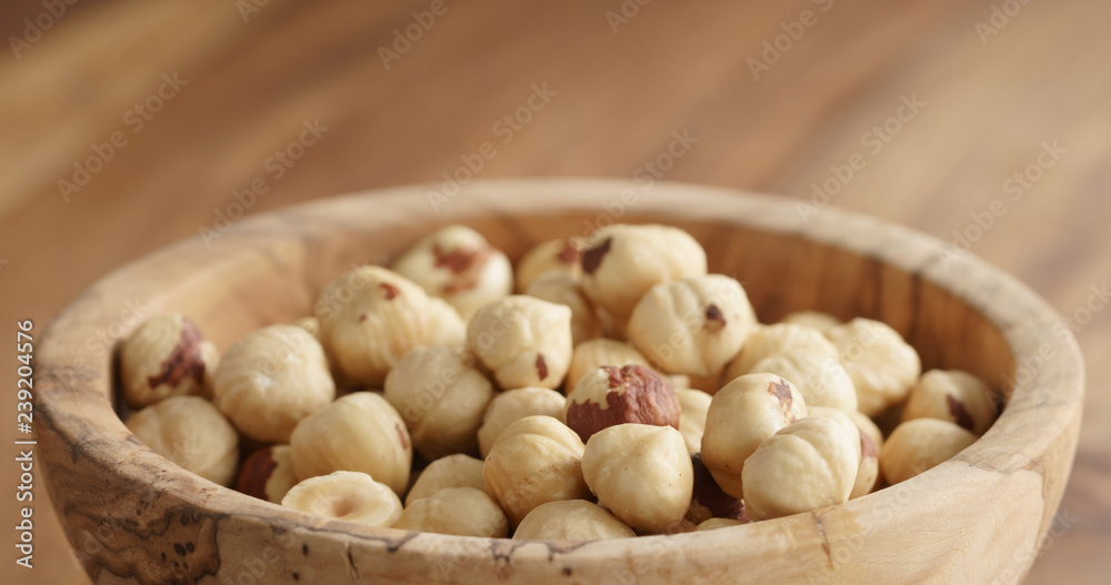 Closeup of roasted hazelnuts in wood bowl on wooden table Closeup of roasted hazelnuts in wood bowl on wooden table