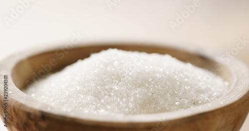 Closeup of white sugar in wood bowl on wooden table