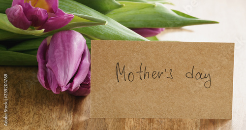 Closeup   of bouquet of purple tulips on wood table with mothers day paper card