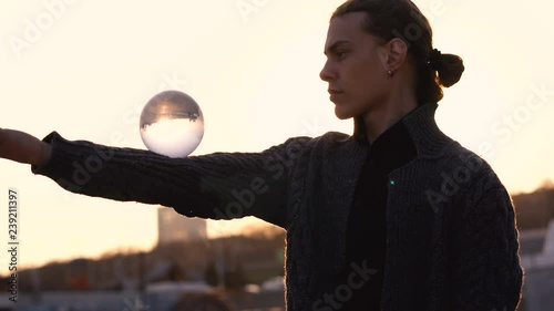 Contact juggling. Man juggle clear acrylic ball on background of urban landscape. Skyline. Magic movement. Performance on street.