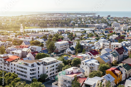 Panoramic view from above on cozy city neighborhood with green trees, pond and sea harbour in clear sunny summer day. Reykjavik, Iceland photo
