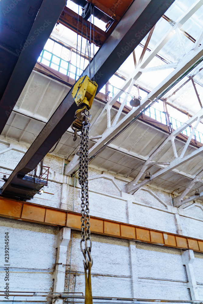 Metallic industrial hook for lifting heavy thing in the factory. Crane chain and hook inside factory background.