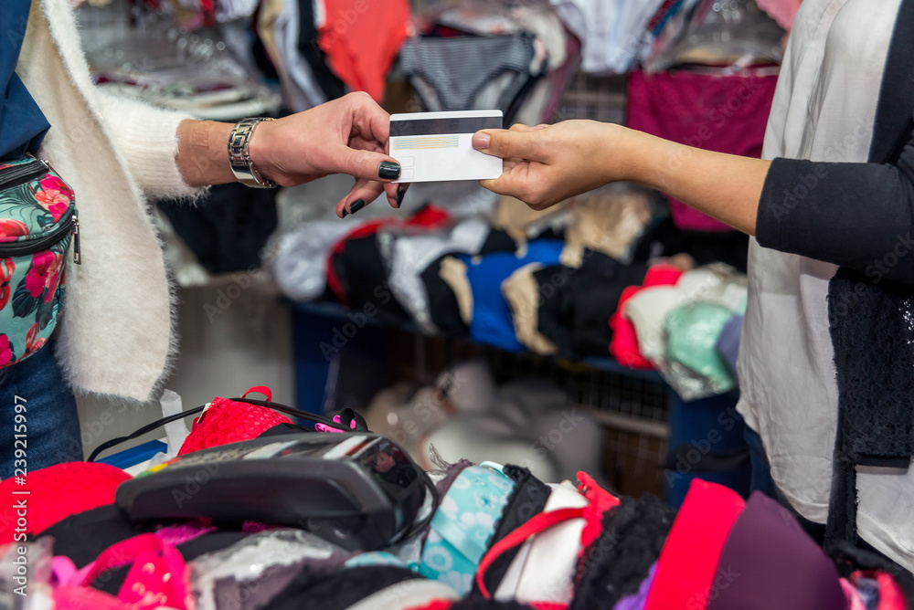 Client giving credit card for payment in underwear shop Client giving credit card for payment in underwear shop