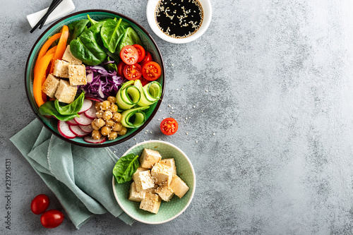Buddha bowl salad with chickpeas, sweet pepper, tomato, cucumber, red cabbage kale, fresh radish, spinach leaves and tofu cheese, healthy balanced clean eating concept, top view, space for a text