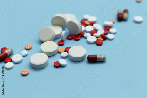 Assorted multicolored pills on blue background closeup
