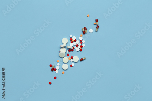 Multicolored pills on blue background closeup