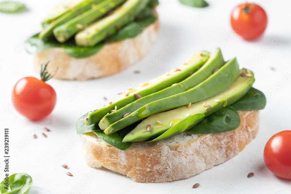 Two ciabatta toast with sliced avocado olive oil, spinach and flax and sesame seeds. Healthy vegetarian Breakfast on white background Two ciabatta toast with sliced avocado olive oil, spinach and flax and sesame seeds. Healthy vegetarian Breakfast on white background