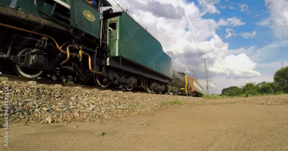 Low shot of a steam locomotive with carriages passing on a sunny day Low shot of a steam locomotive with carriages passing on a sunny day