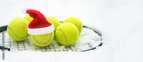 Santa hat on tennis ball, set of tennis balls on racket on white snow winter background. Merry Christmas and New year concept with tennis balls play. Close up, sport lifestyle, funny. Isolated © IrynaV