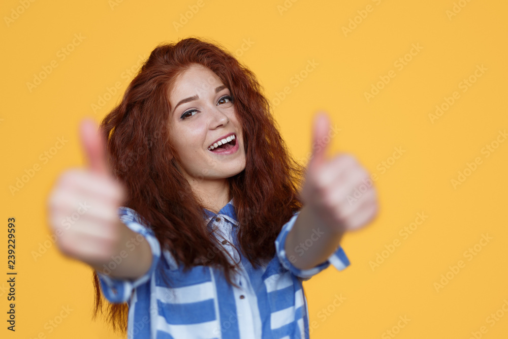Cheerful red-haired woman gesturing thumb-up