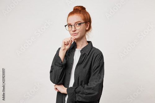 Canvas-taulu Portrait of young red -hair female in black men's shirt, keeps arm on chin and l
