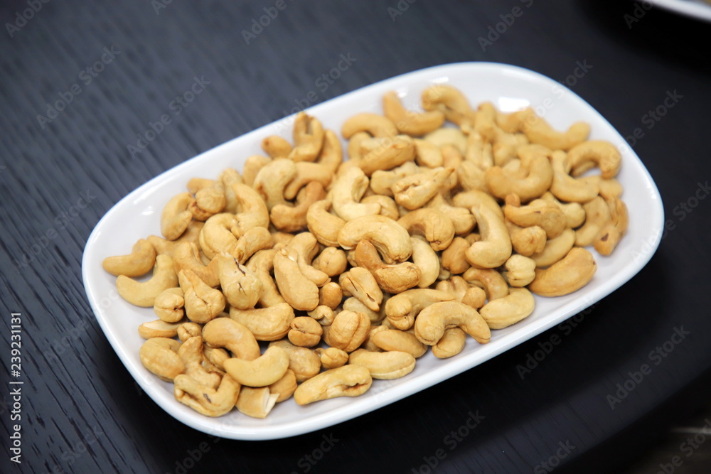 Cashew nuts in white plate On the black wood table Cashew nuts in white plate On the black wood table