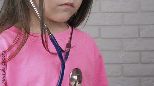 Kid listening heart with a stethoscope. Little girl plays with a stethoscope. photo