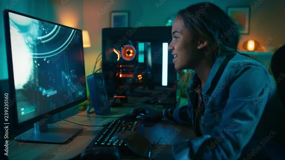 Beautiful and Excited Black Gamer Girl is Playing First-Person Shooter Online Video Game on Her Computer. Room and PC have Colorful Neon Led Lights. Cozy Evening at Home.