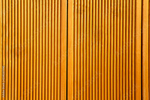 Yellow wooden wall panels decorated with vertical grooves. Abstract geometrical carved wood background