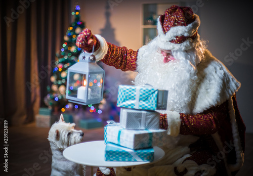 Santa Claus with a candle lantern looking at gifts. Santa brings and distributes gifts.
