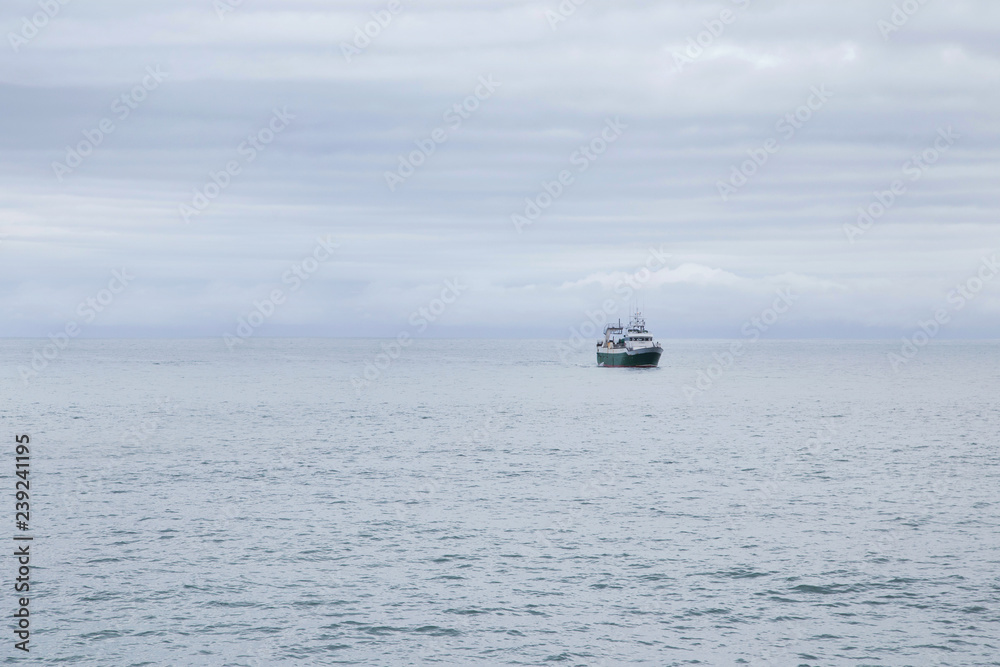 Fishing boat at sea on a cloudy morning. Alone into the big ocean.