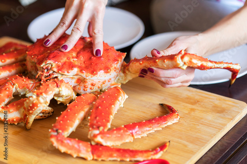 women's hands is taking leg from big red cooked crab for food photo