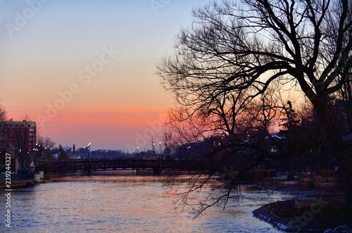 Light comes on along streets and bridges spanning the Fox River as dusk overtakes sunset in the river city of Elgin, Illinois.