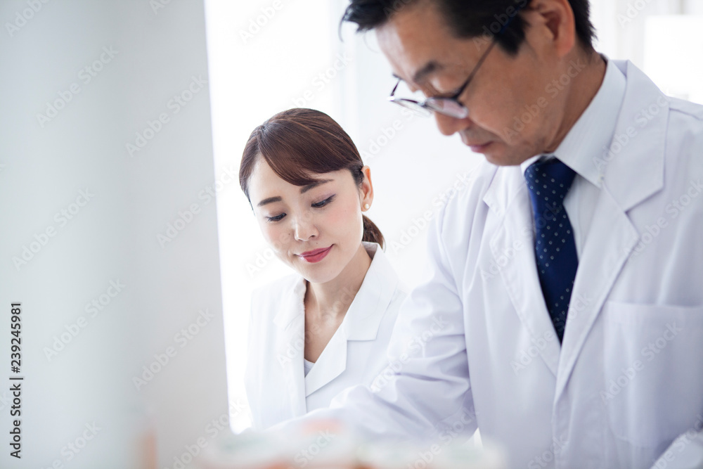 研究員の上司と部下が協力して実験に取り組んでいる 研究員の上司と部下が協力して実験に取り組んでいる