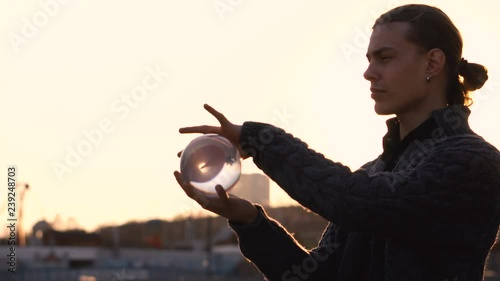 Contact juggling. Man juggling with transparent acrylic ball against background of cityscape. Skyline. Magic of movement. Performance in street.