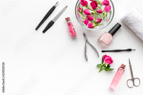 manicure equipment with nail polish and rose petals white background top view space for text