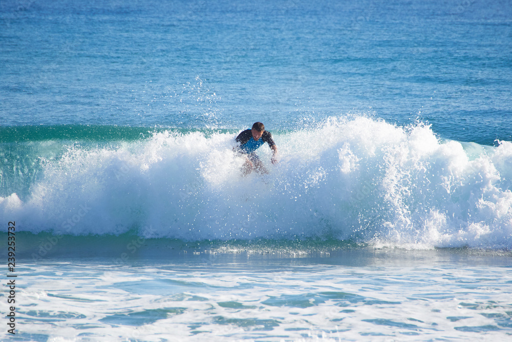 Naklejka premium man in the ocean on a surfboard rides on top of a wave