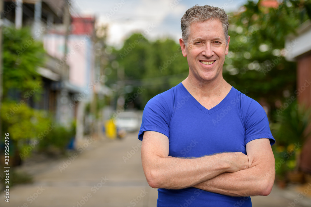 Happy mature man smiling with arms crossed in the streets outdoors Happy mature man smiling with arms crossed in the streets outdoors