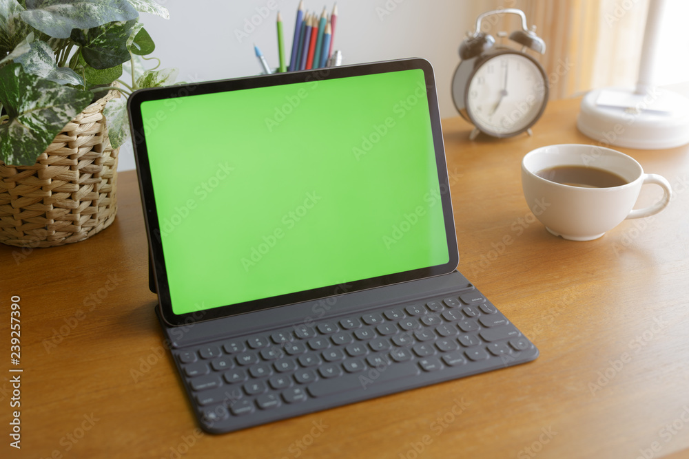 Empty tablet has a green screen on the desk by the window. Empty tablet has a green screen on the desk by the window.