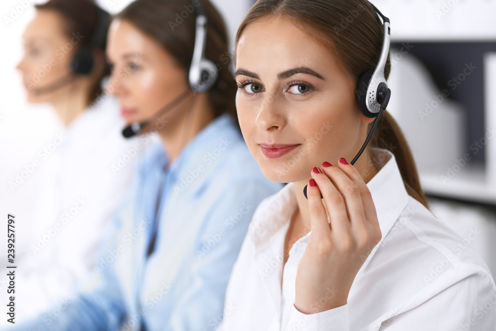 Call center. Group of operators at work. Focus at beautiful business woman in headset