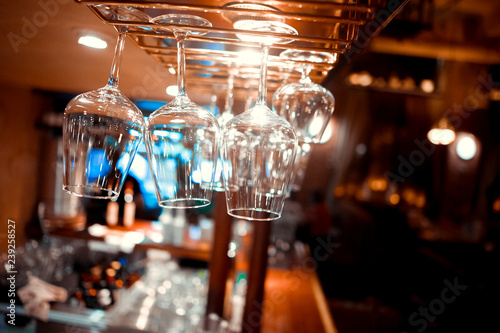 Glasses of wine. Glasses hanging above the bar in the restaurant. Empty glasses for wine. Wine and martini glasses in shelf above a bar rack in restaurant. blue lights  blue background  night life