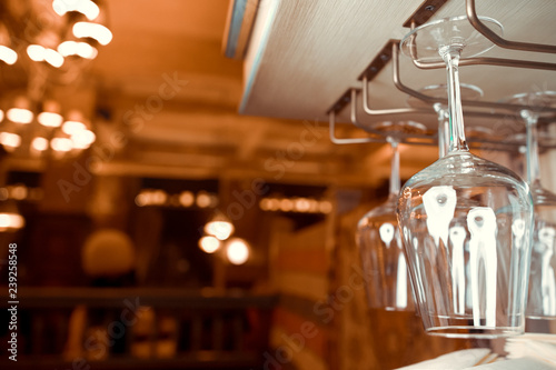 Glasses of wine. Glasses hanging above the bar in the restaurant. Empty glasses for wine. Wine and martini glasses in shelf above a bar rack in restaurant. blue lights, blue background, night life