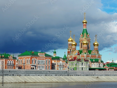Orthodox Church on the coast of beautiful river. Colorful background with golden domes.