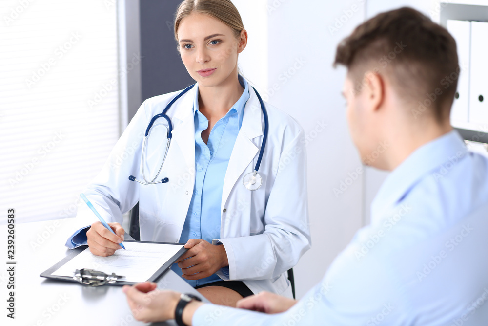 Doctor and patient in hospital. Beautiful blonde physician consulting business man about his health. Medicine concept Doctor and patient in hospital. Beautiful blonde physician consulting business man about his health. Medicine concept