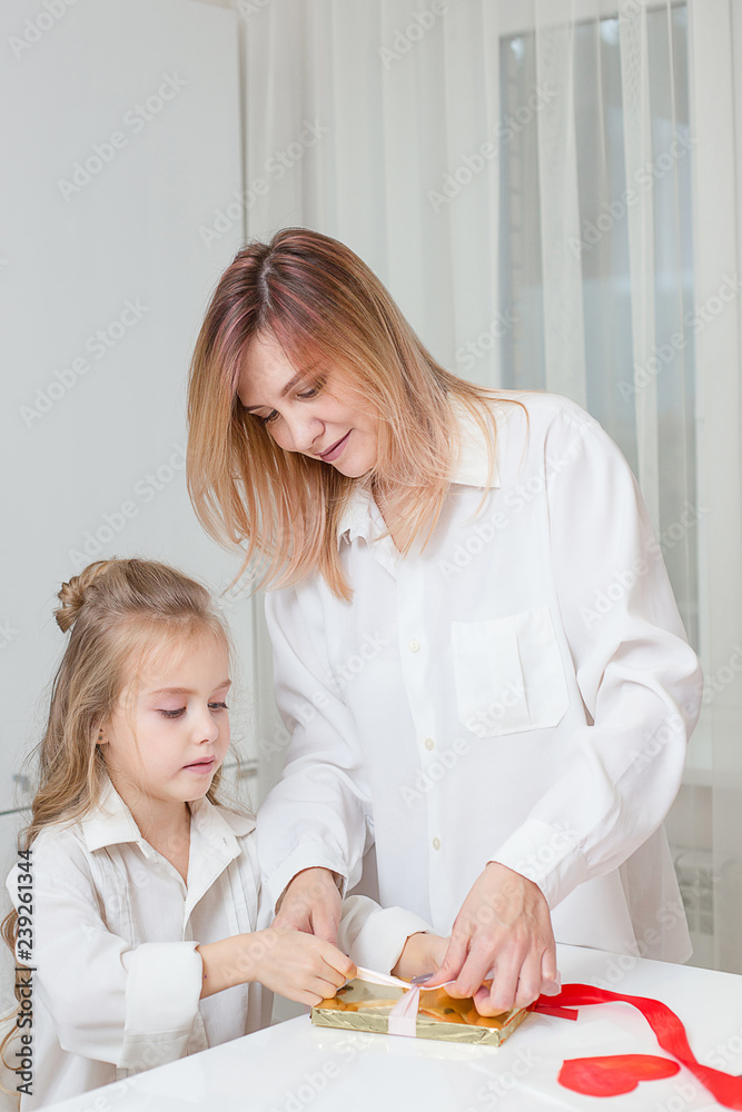 mother and daughter a wrapping a gift together mother and daughter a wrapping a gift together