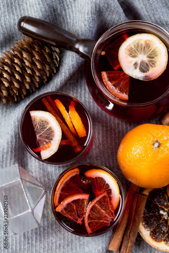 Mulled wine in glasses with orange and spices with gray scarf.