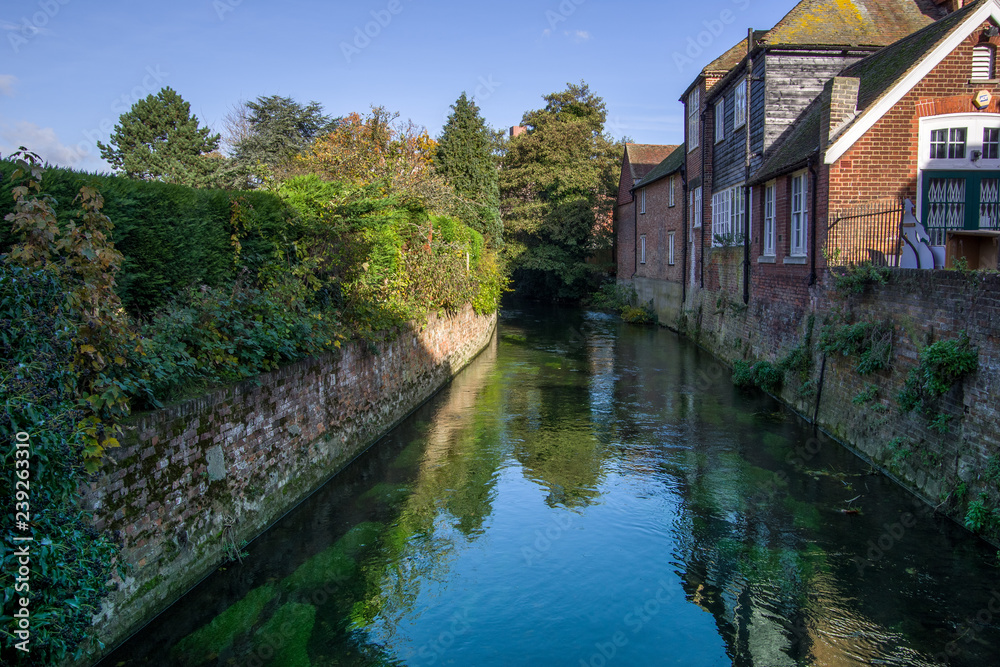 Landscape view of river Great Stour passing near houses. Green trees in the background. Canterbury, United Kingdom. Landscape view of river Great Stour passing near houses. Green trees in the background. Canterbury, United Kingdom.