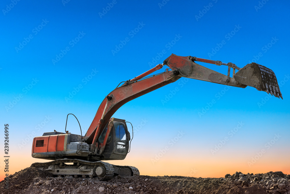 Excavator work on construction site at sunset Excavator work on construction site at sunset