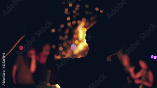 Man dancing in front of a fire at night. Package of two scenes, panning right, seen from behind, at night