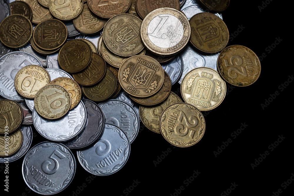 Ukrainian coins with one euro coin isolated on black background. Close-up view. Coins are located at the left side of frame. A conceptual image. Ukrainian coins with one euro coin isolated on black background. Close-up view. Coins are located at the left side of frame. A conceptual image.