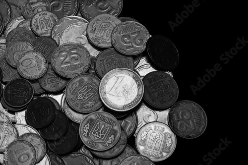 Ukrainian coins with one euro coin isolated on black background. Black and white image. Close-up view. Coins are located at the left side of frame. A conceptual image.