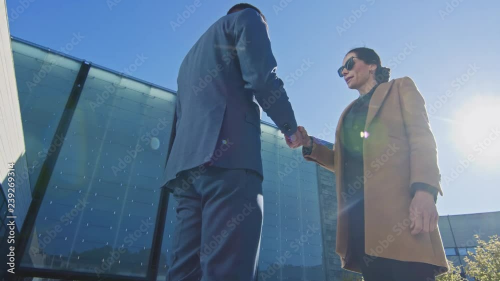 Elegant Businesswoman Meets with Handsome Businessman, They Shake Hands and Start Talking Business. Smart Confident People Doing Business in Urban City Area. Arc Camera Shot.