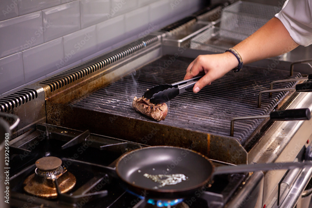 Chef making beef on restaurant grill. Making great food Chef making beef on restaurant grill. Making great food