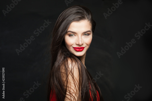 Smiling brunette woman with long straight healthy hair on black background