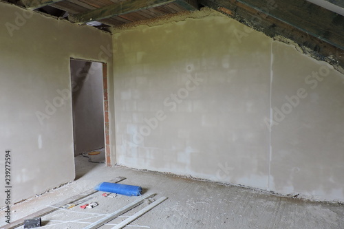 Walls of an empty room under construction covered with hard plaster and some mess