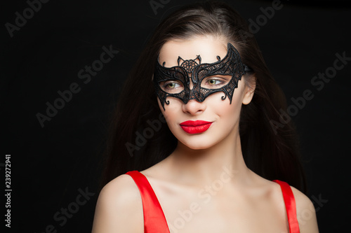 Fashion brunette woman with red lips makeup wearing carnival mask on black background, halloween portrait